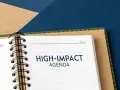 A notebook open to a page titled "HIGH-IMPACT AGENDA," ready for a productive board meeting.
