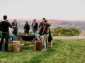 Staff retreat ideas for nonprofits: A group enjoys a bonfire and drinks outdoors, surrounded by rolling hills.